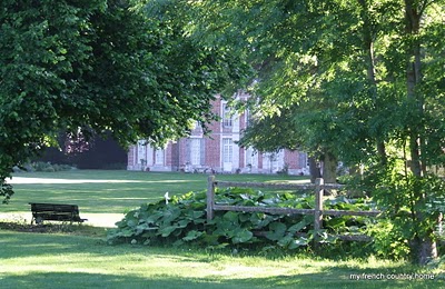 visiting-valley-rose-gardens-miserey-my-french-country-home glimpse of the manor through trees in the garden