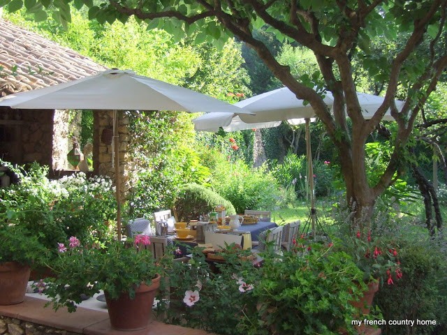 vibrant garden with outdoor dining space and white umbrellas