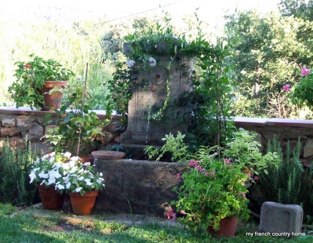 stone well in the garden, covered with flowers and ivy