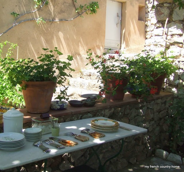 summertime-living-easy-2-my-french-country-home an outdoor table with items for a table setting and potted plants