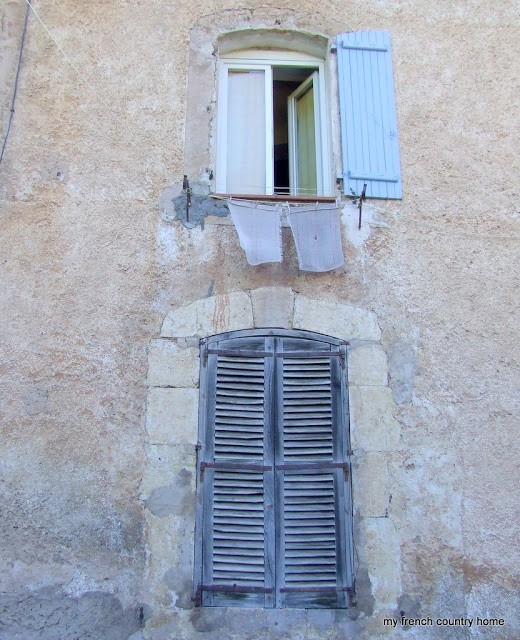 beige stone wall with blue-shuttered windows