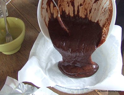 chocolate batter being poured into lined tart pan