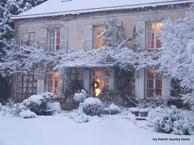 snowy home with lit windows