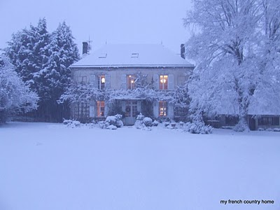 manor home covered in snow with large snow-covered lawn