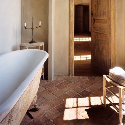 bathroom in terra cotta and creams, with large bathtub and tiled floor