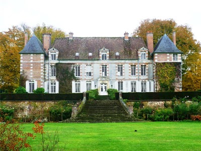 back of a large chateau with wide steps leading down to a lawn