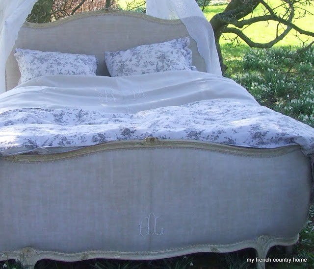 upholstered bed frame with fluffy white and blue floral linens