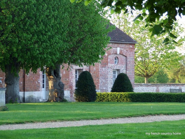 brick manor home half-hidden behind trees