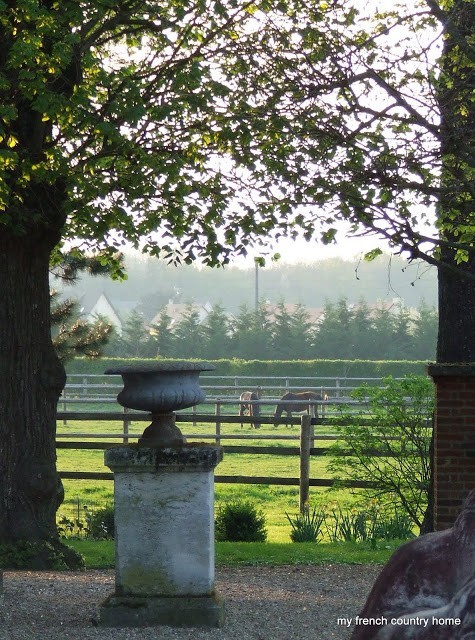 cement urn on a pedestal, in front of a horse pasture