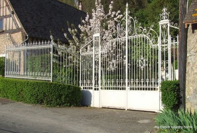 early-sunday-brocante-my-french-country-home white wrought-iron gate with flowering tree behind