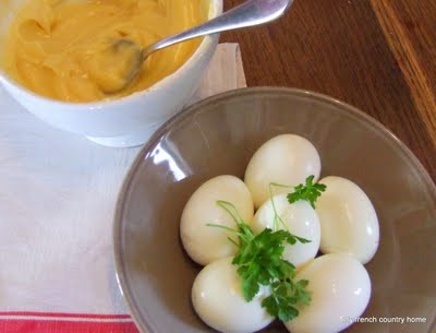 hard-boiled eggs in a bowl with parsley, with a bowl of homemade mayonnaise next to it