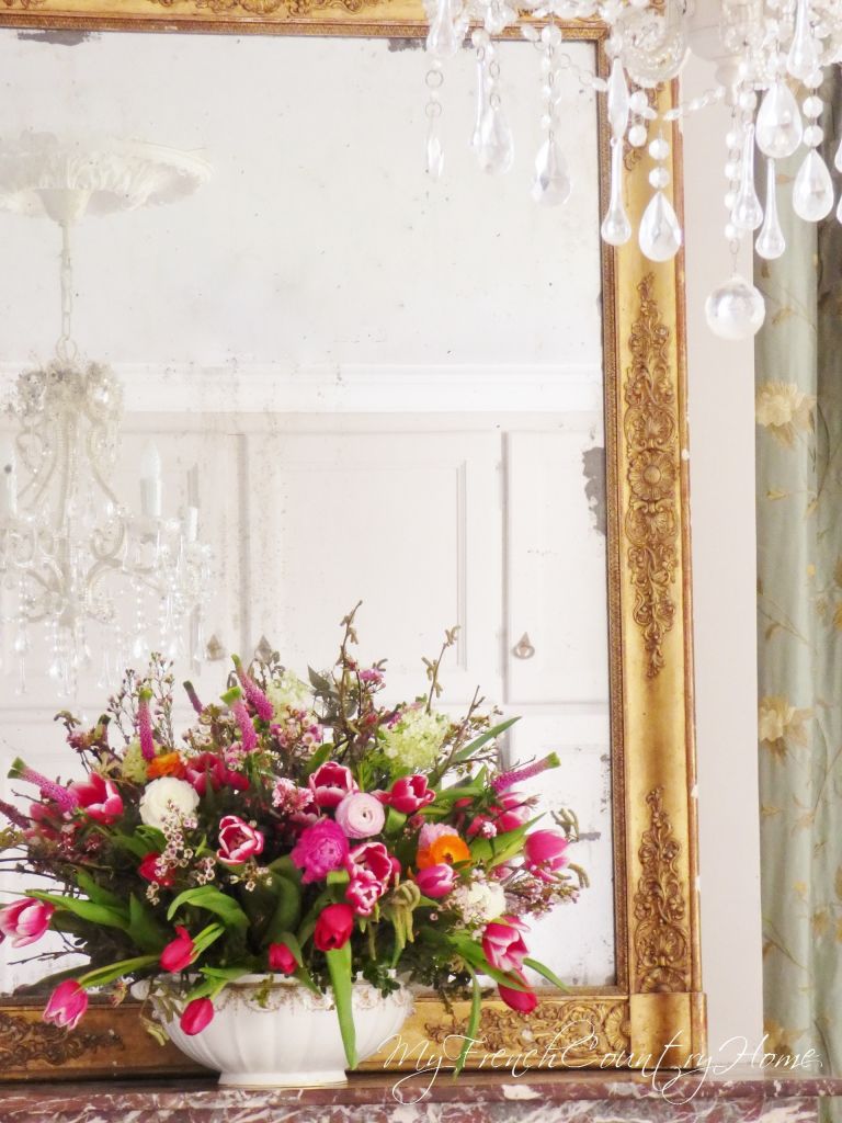 pink flower arrangement in front of antique mirror