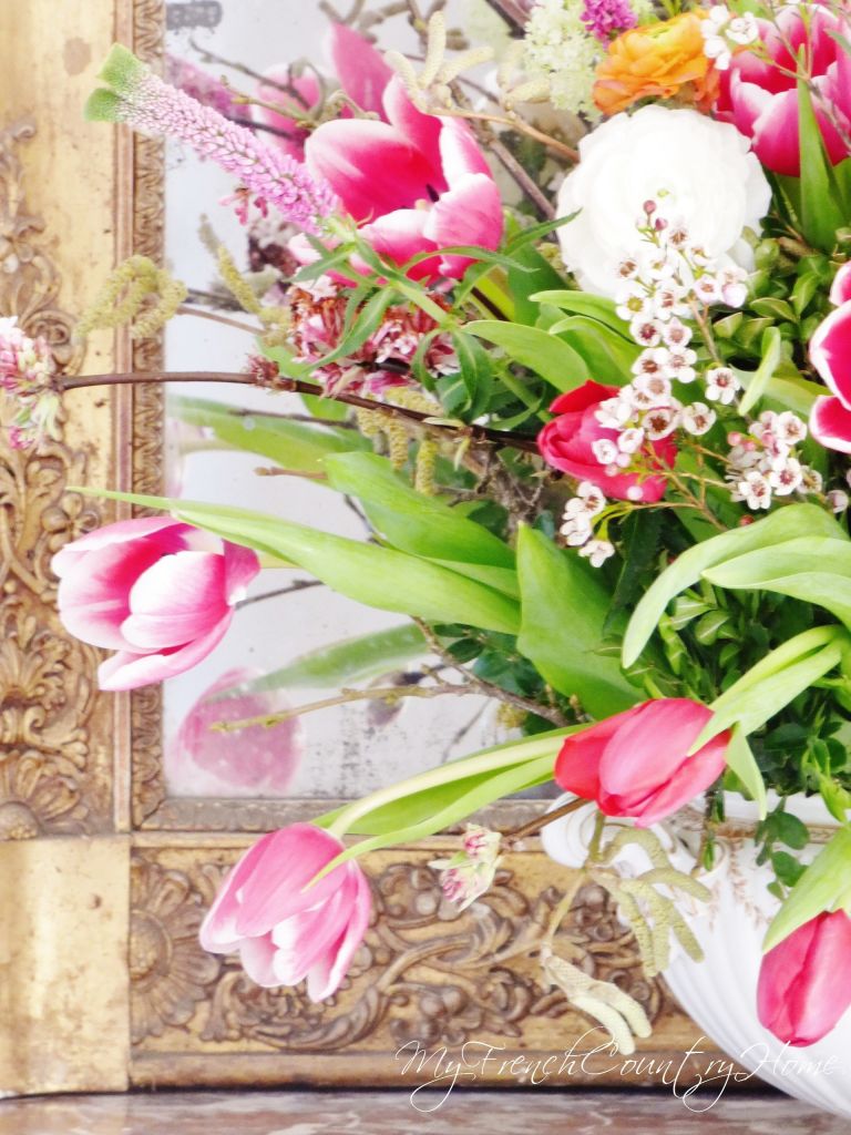 pink flower arrangement in front of antique mirror