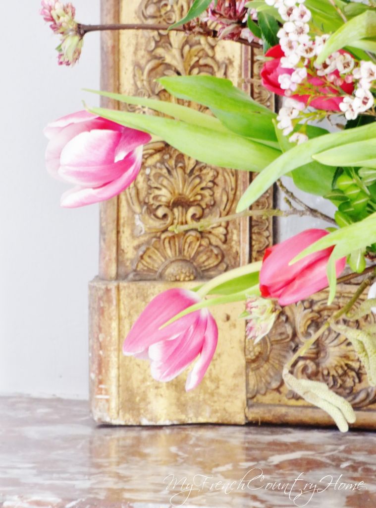 pink flower arrangement in front of antique mirror