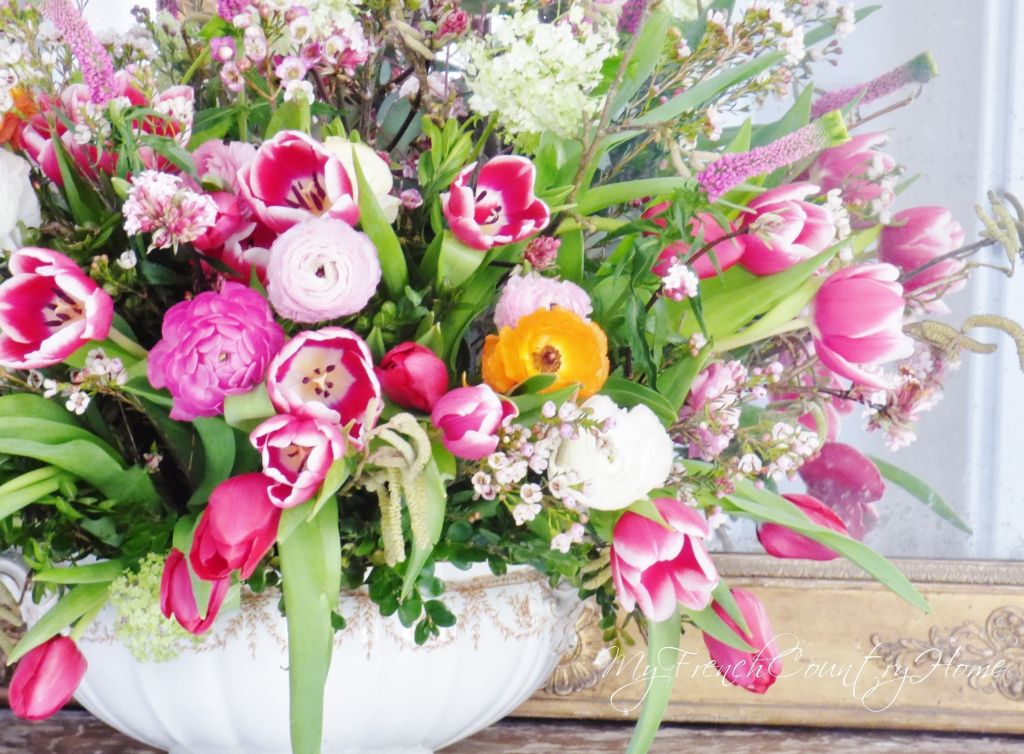 pink flower arrangement in front of antique mirror
