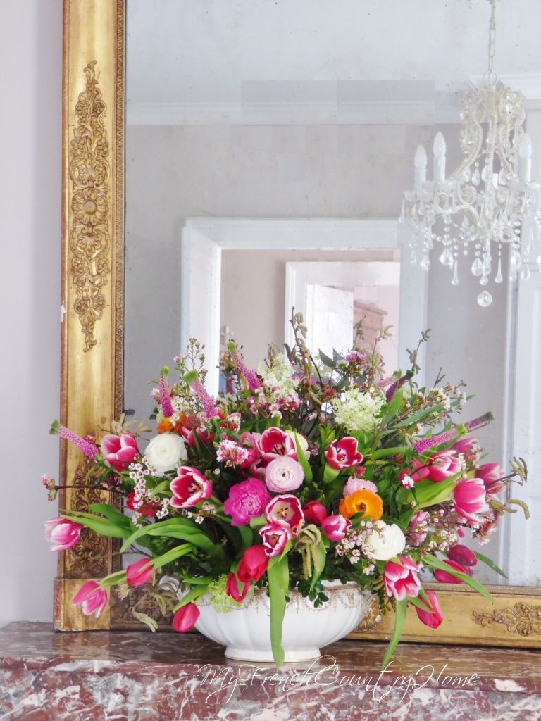 pink flower arrangement in front of antique mirror