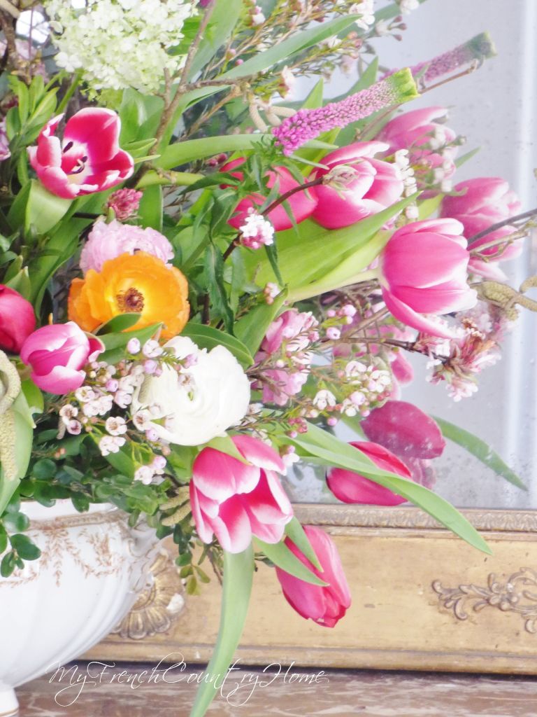 pink flower arrangement in front of antique mirror