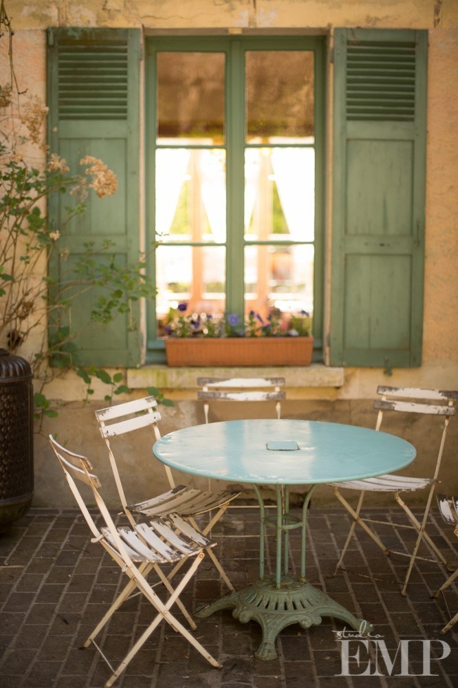 table and chairs outside blue shuttered window