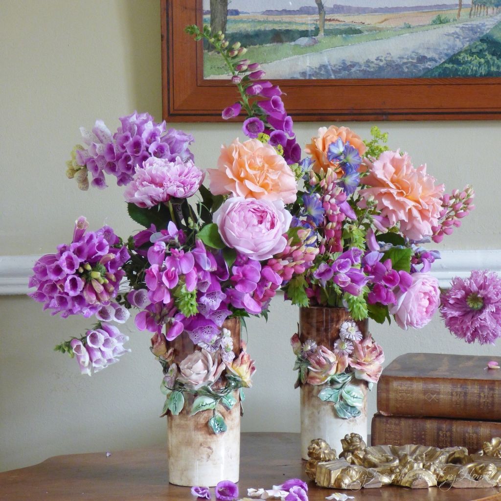 roses and foxgloves arranged in antique vases