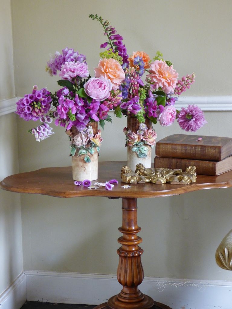 roses and foxgloves arranged in antique vases