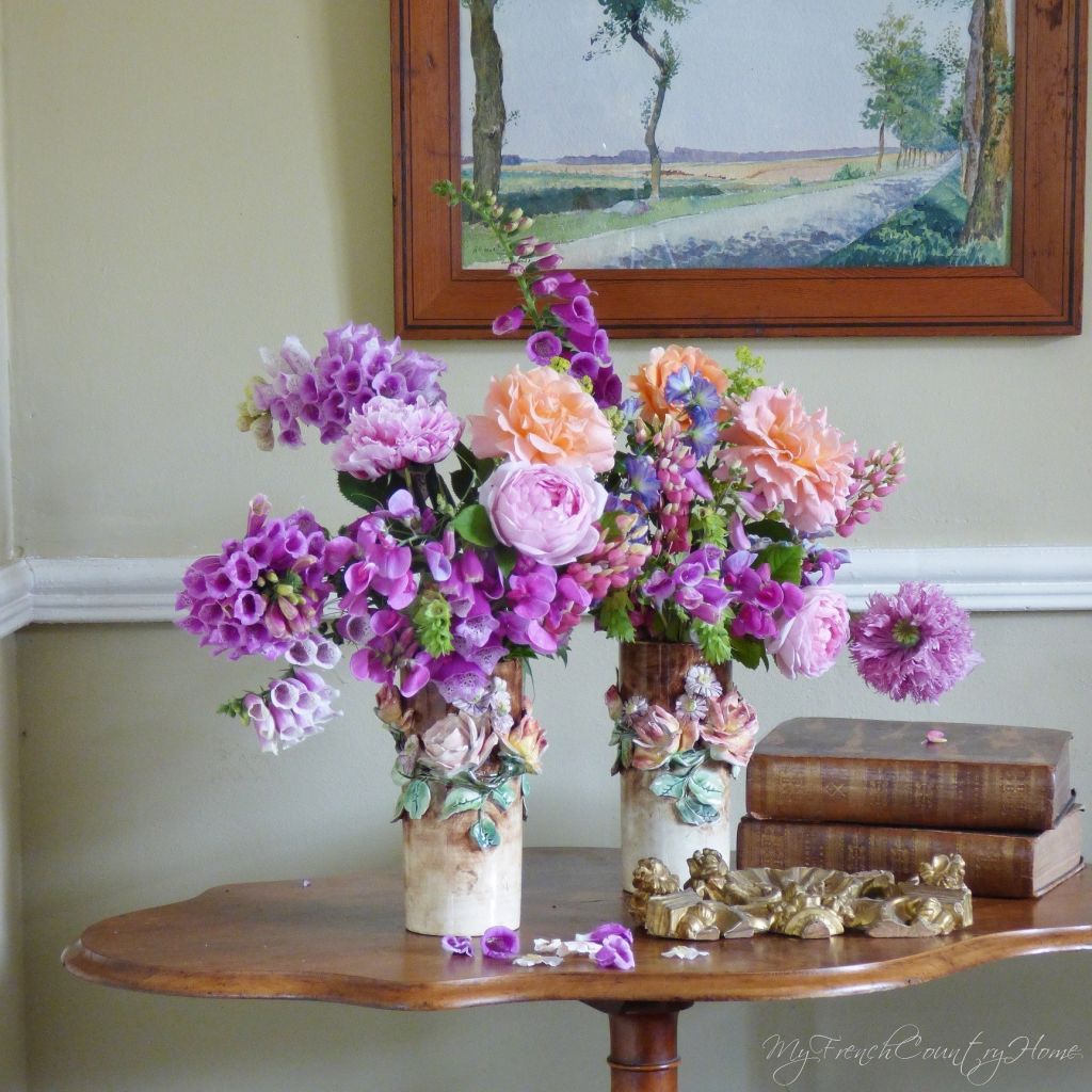 roses and foxgloves arranged in antique vases