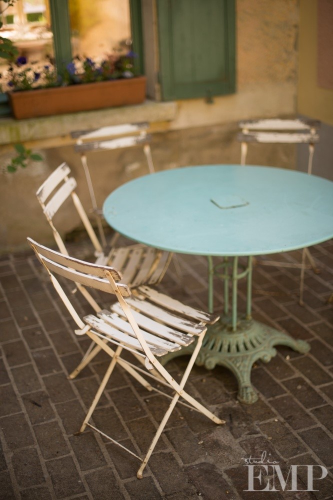 white folding chairs around french blue metal garden table