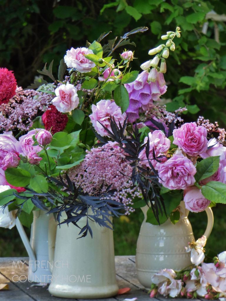 roses and garden flowers in white jugs