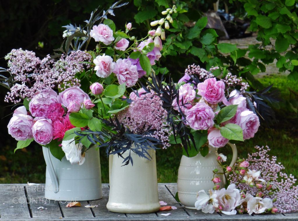 roses and garden flowers in white jugs