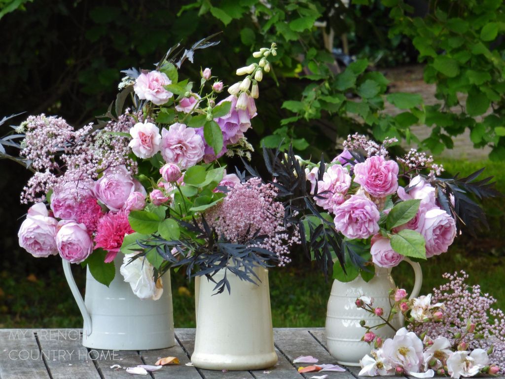 roses and garden flowers in white jugs
