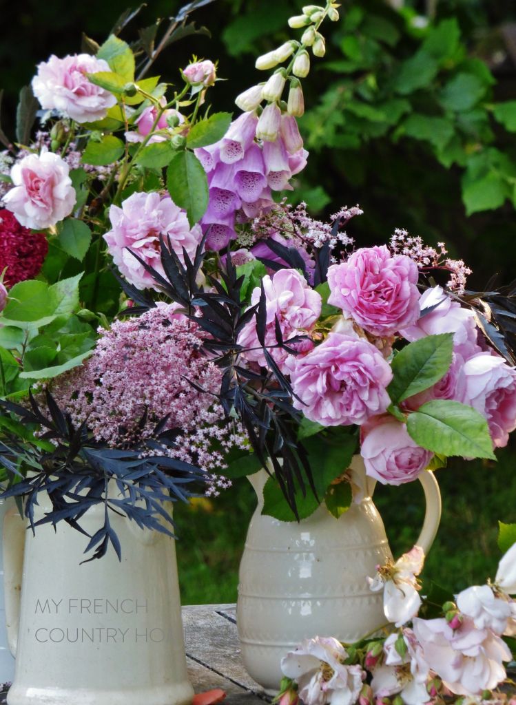 roses and garden flowers in white jugs