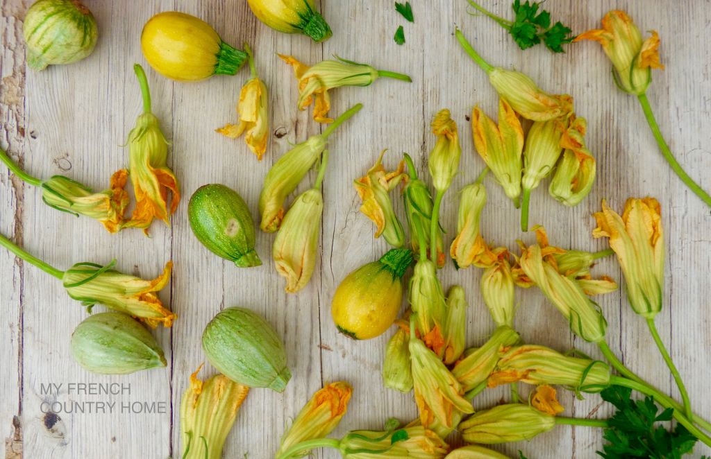 baby courgettes and courgette flowers on wooden table