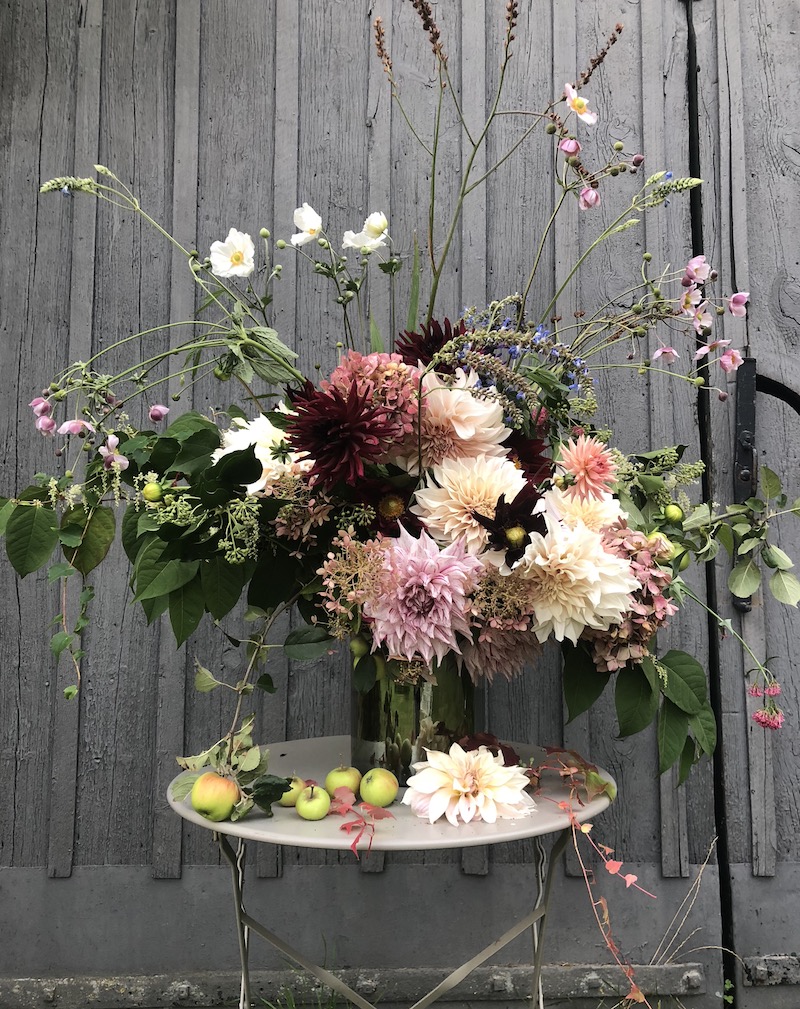 autumn flowers arranged in vase outside barn