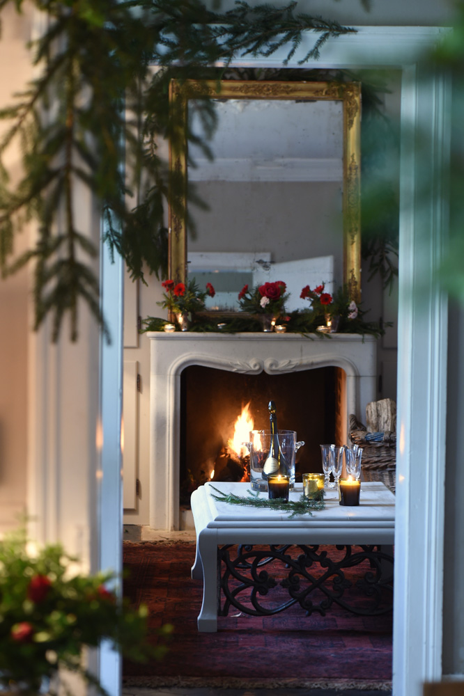 View into living room with marble fireplace and red flower decorations on the mantle- red christmas decoration ideas- MY FRENCH COUNTRY HOME