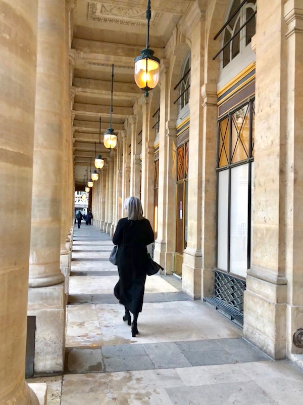 in true parisian style a woman walking through building in paris