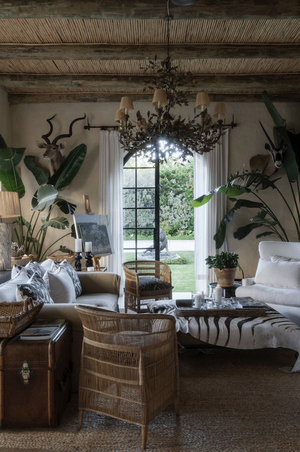 living room decorated with plants, chandelier, white couches and wicker furniture