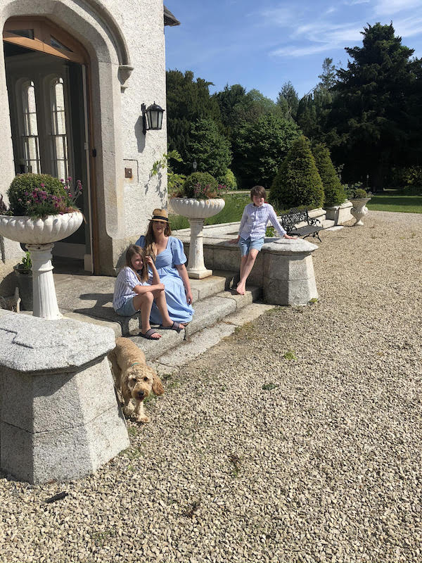 mother and two children and dog on steps of manor home