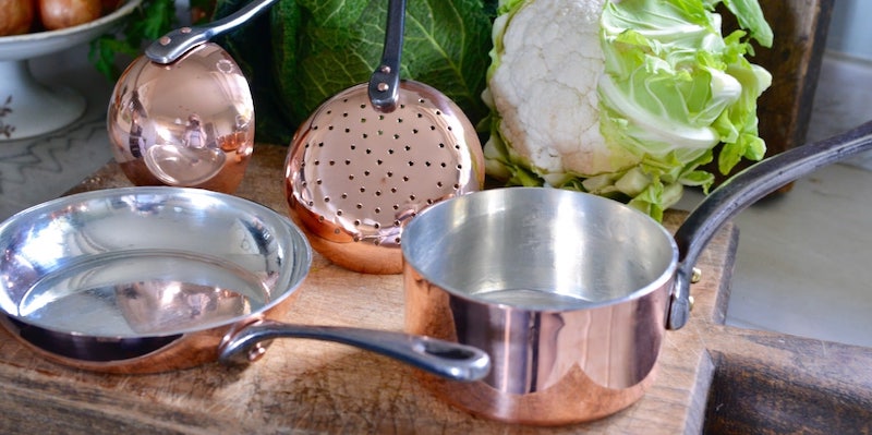 set of copper pans and utensils on cutting board
