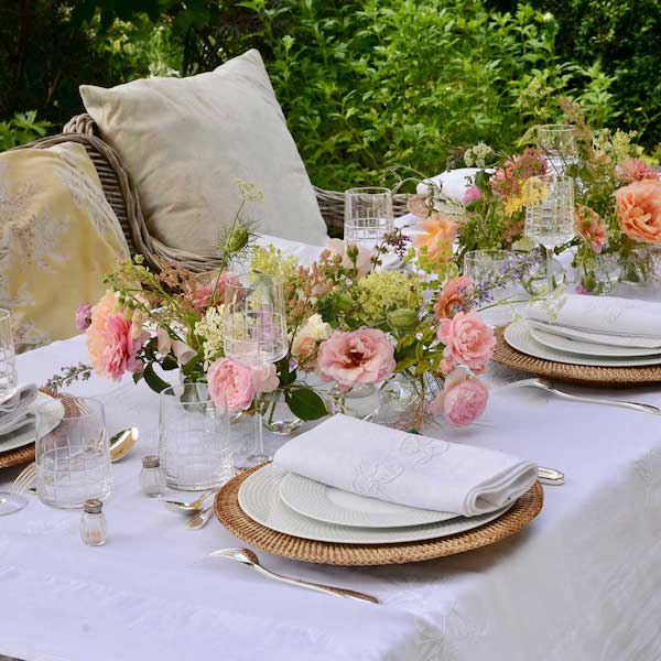 outdoor tablescape with plates, napkins and flowers