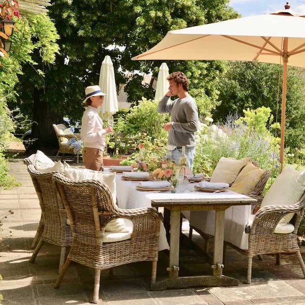 outdoor dining table with umbrella and boy and woman talking