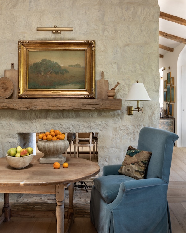 wooden kitchen table with bowls of fruit and a blue armchair