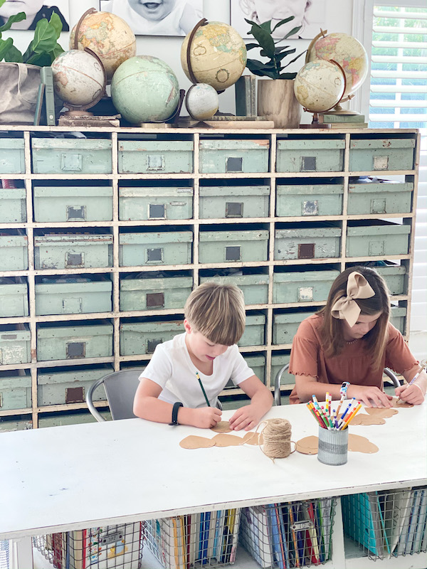 children writing at desk with storage